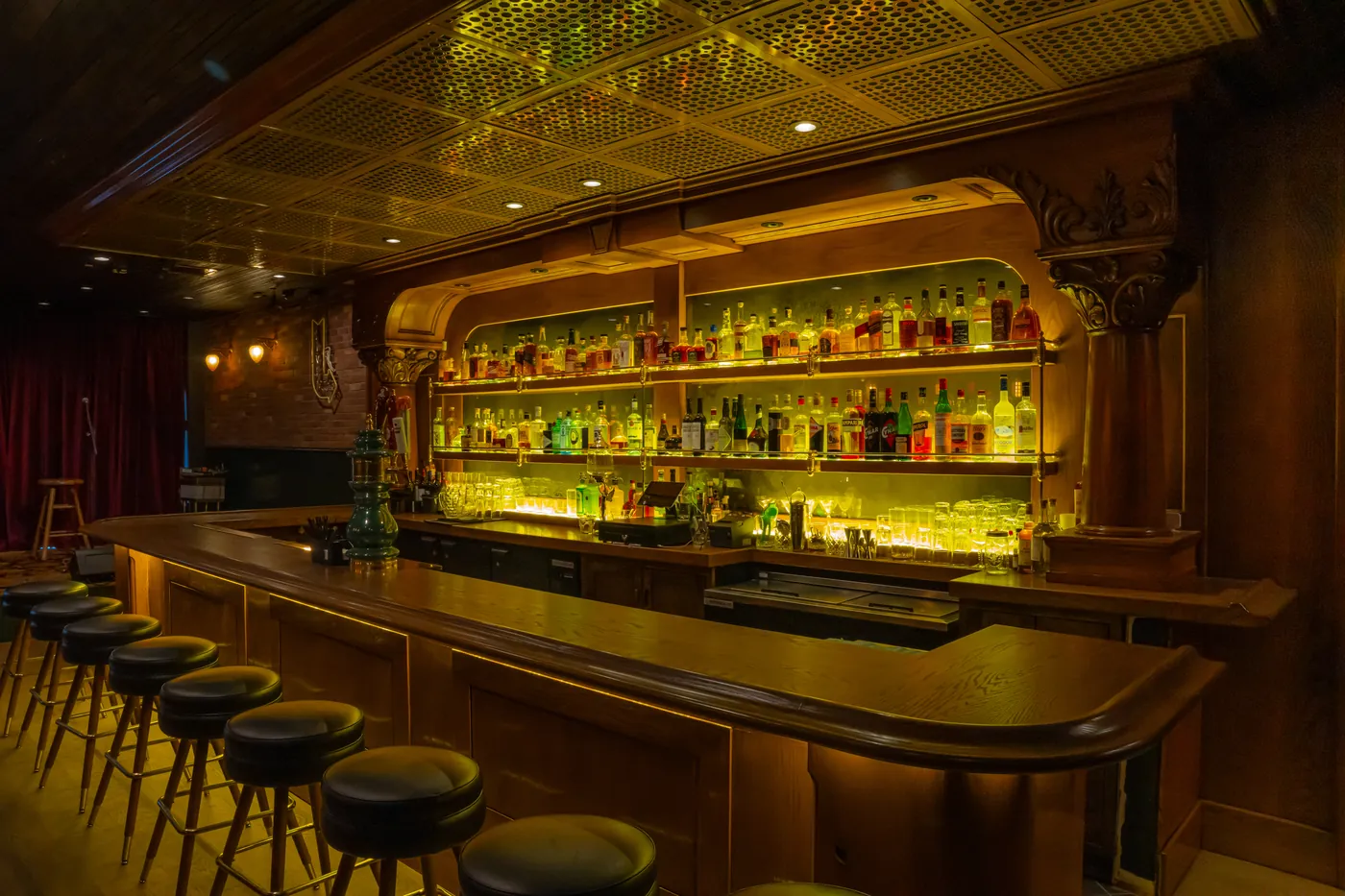 Ornate golden back bar with bottles glowing in an empty saloon