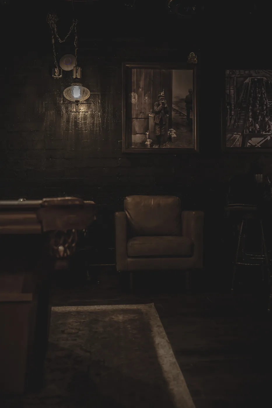 Dark vintage room with a leather armchair, framed pictures and long shadows