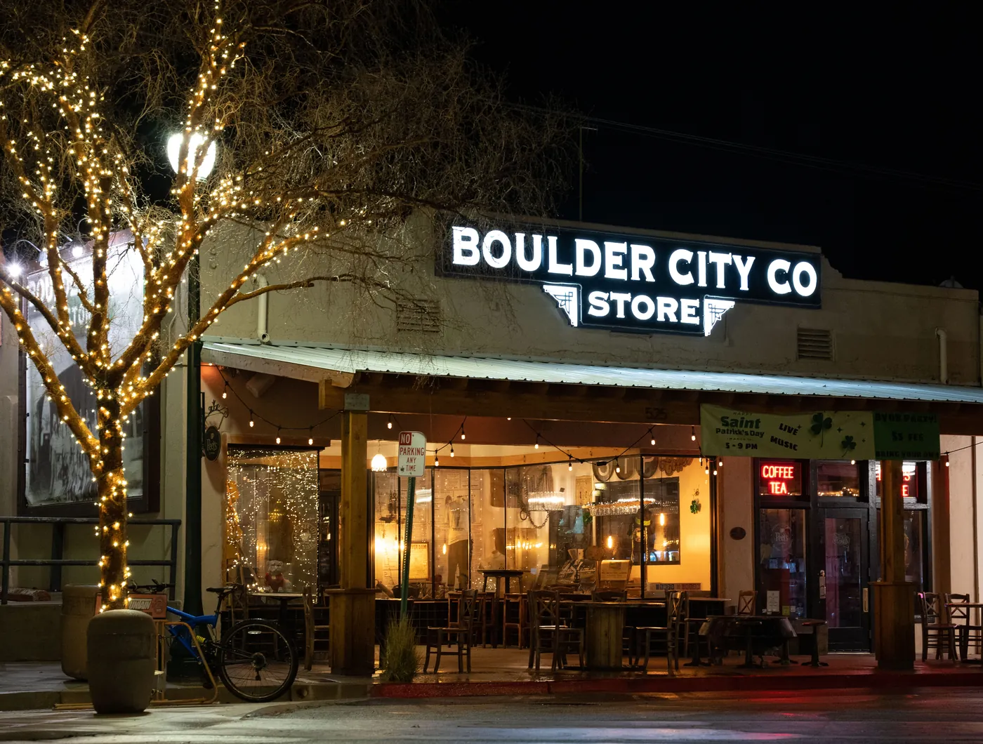 Boulder City Co. store glowing at night with string-lit trees after rain in Boulder City, Nevada